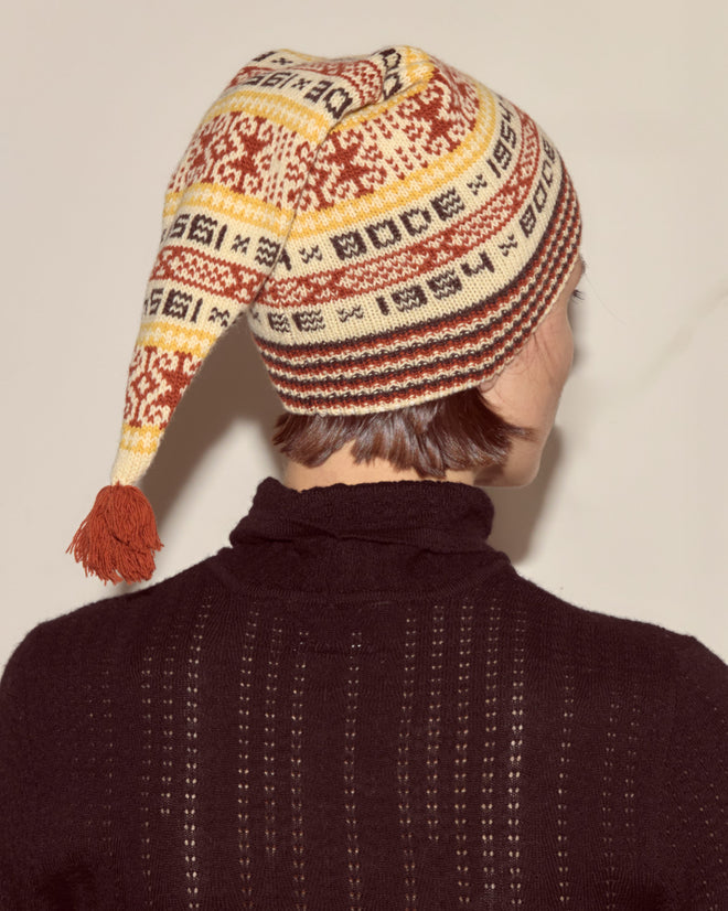 Person shown from behind wearing the Marzipan Hat, a 100% wool Norwegian-patterned hat with a tassel, set against a plain background.
