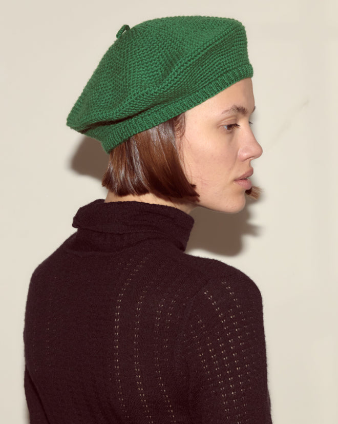 A person in a green Crochet Beret and black turtleneck, shown from the side against a plain background, showcases classic style with vintage accessories.