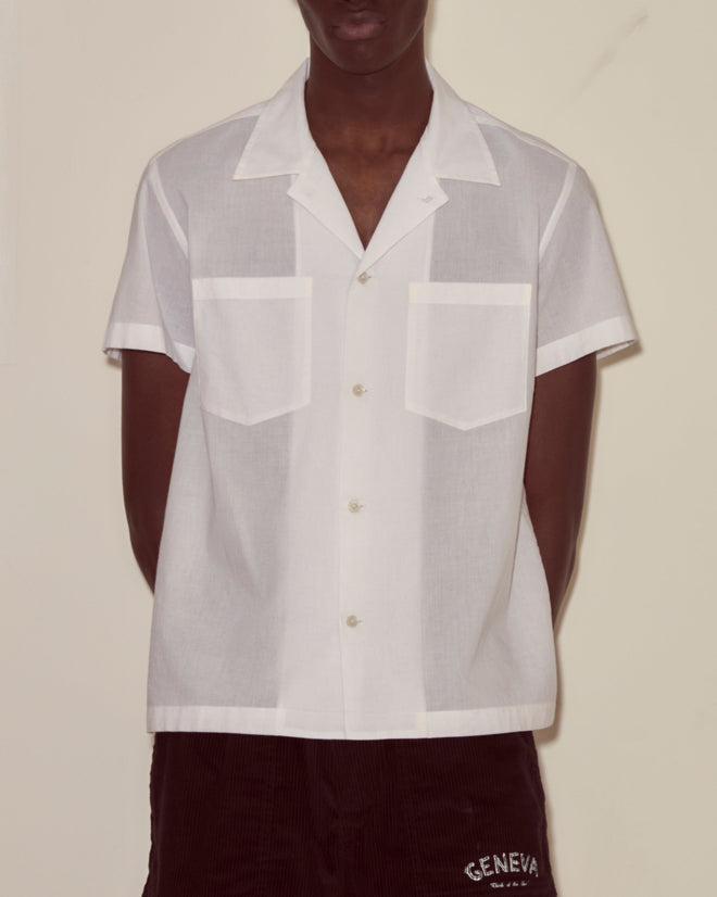 A person wearing the Voile Short Sleeve Shirt - White and dark shorts stands against a plain background.