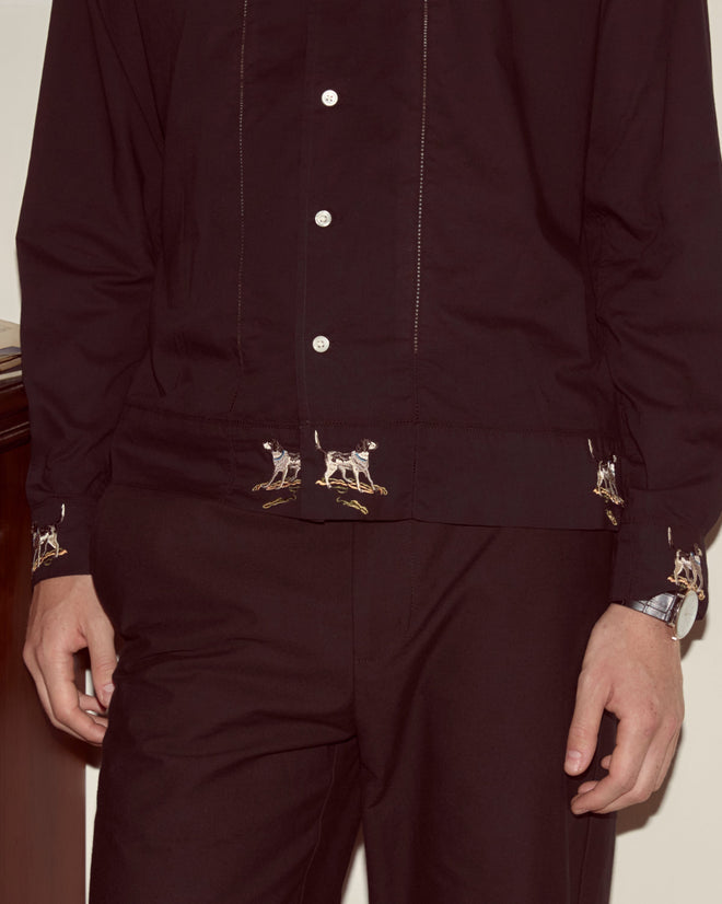 Person wearing the Pointer Long Sleeve Shirt, a black cotton top with ladderwork details and an embroidered dog motif near the cuffs, paired with matching dark trousers.